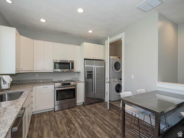 13772 S Kennington Ct E, Draper, UT 84020 - kitchen featuring appliances with stainless steel finishes, stacked washer / dryer, a sink, dark wood-type flooring, and white cabinets