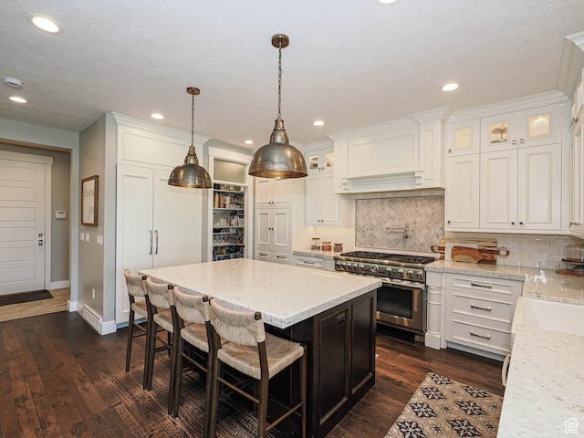 13772 S Kennington Ct E, Draper, UT 84020 - kitchen featuring range with two ovens, white cabinets, decorative backsplash, a center island, and dark wood finished floors