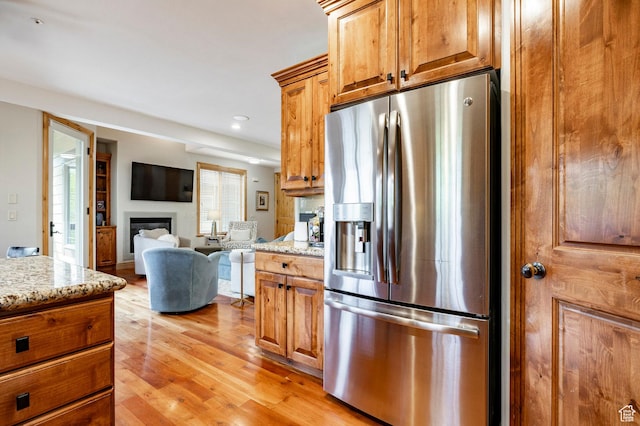 3006 E Canyon Links Dr S, Park City, UT 84098 - kitchen with stainless steel fridge, a glass covered fireplace, light stone counters, light wood-style floors, and recessed lighting
