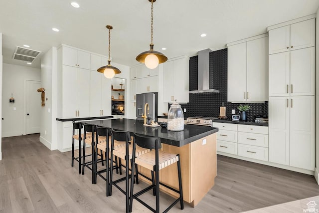 1585 E Black Brush Dr Unit 61, Washington, UT 84780 - kitchen with wall chimney range hood, dark countertops, light wood finished floors, a breakfast bar area, and recessed lighting