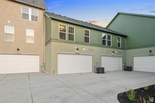 11433 S Watercourse Rd Unit 184, South Jordan, UT 84009 - back of property featuring a garage, stucco siding, central AC unit, and driveway