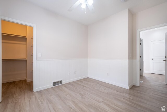 10227 S Oquirrh Lake Rd, South Jordan, UT 84095 - unfurnished bedroom featuring a walk in closet, wood finished floors, wainscoting, a closet, and ceiling fan