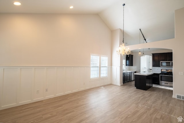 10227 S Oquirrh Lake Rd, South Jordan, UT 84095 - living room with a chandelier, high vaulted ceiling, a wainscoted wall, a decorative wall, and arched walkways