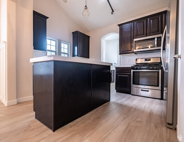 10227 S Oquirrh Lake Rd, South Jordan, UT 84095 - kitchen with appliances with stainless steel finishes, light wood-style flooring, arched walkways, backsplash, and lofted ceiling