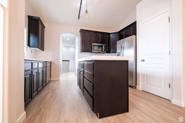 10227 S Oquirrh Lake Rd, South Jordan, UT 84095 - kitchen featuring appliances with stainless steel finishes, arched walkways, a kitchen island, light wood-style flooring, and lofted ceiling