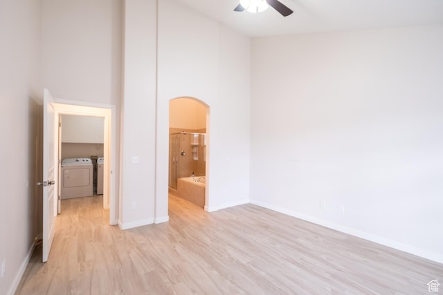 10227 S Oquirrh Lake Rd, South Jordan, UT 84095 - unfurnished bedroom featuring washing machine and dryer, arched walkways, light wood-style floors, baseboards, and ensuite bathroom
