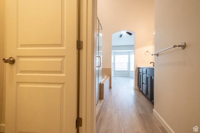 10227 S Oquirrh Lake Rd, South Jordan, UT 84095 - hall with light wood finished floors, arched walkways, a sink, and baseboards