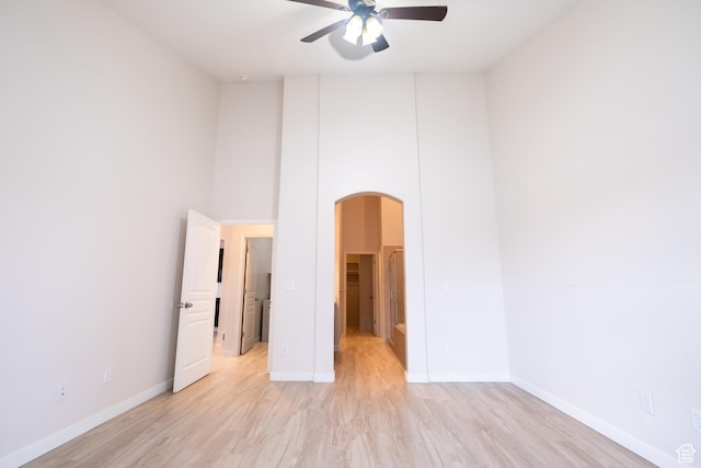 10227 S Oquirrh Lake Rd, South Jordan, UT 84095 - unfurnished bedroom with arched walkways, light wood-type flooring, baseboards, and a walk in closet