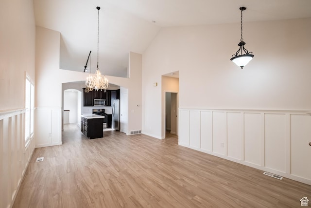 10227 S Oquirrh Lake Rd, South Jordan, UT 84095 - unfurnished living room with a decorative wall, high vaulted ceiling, light wood finished floors, wainscoting, and a chandelier