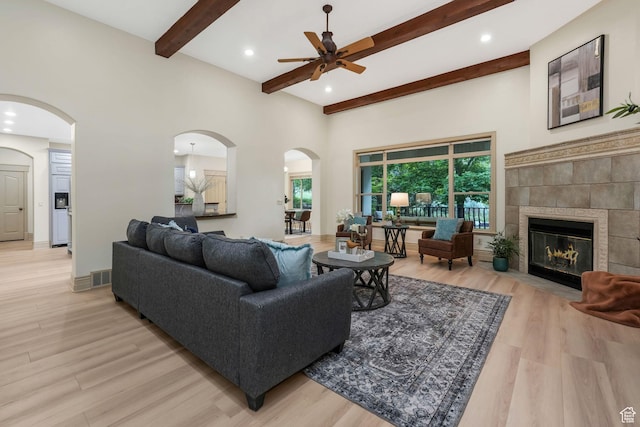 584 S Silver Ln, Alpine, UT 84004 - living room featuring light wood-style flooring, ceiling fan, beamed ceiling, arched walkways, and a tiled fireplace