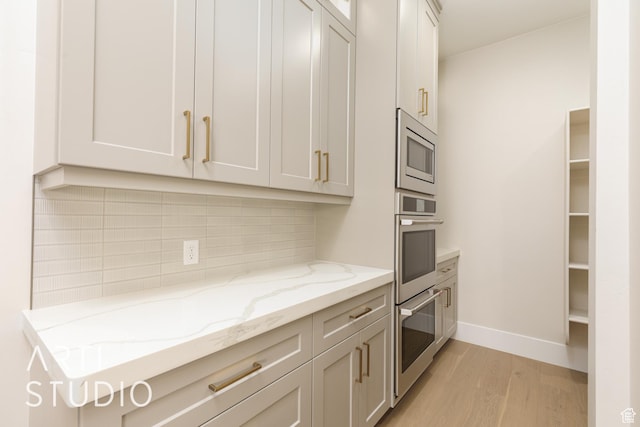 2921 E Yavin Way, St George, UT 84790 - kitchen with stainless steel appliances, light wood-style flooring, tasteful backsplash, light stone counters, and baseboards