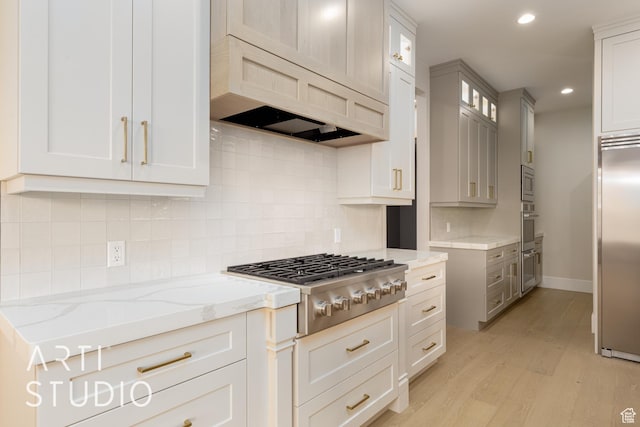 2921 E Yavin Way, St George, UT 84790 - kitchen with built in appliances, light stone countertops, light wood finished floors, glass insert cabinets, and decorative backsplash