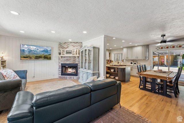 623 N 120 W, Lehi, UT 84043 - living area featuring a textured ceiling, light wood-style floors, recessed lighting, a fireplace, and a ceiling fan