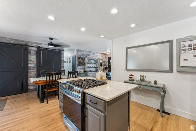 623 N 120 W, Lehi, UT 84043 - kitchen featuring stainless steel gas stove, a barn door, light wood-style flooring, baseboards, and light stone countertops