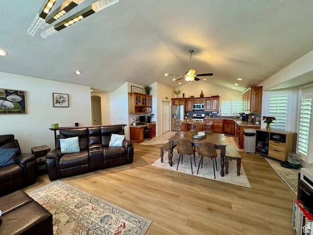 1710 N 2625 E, Layton, UT 84040 - living room featuring vaulted ceiling, a ceiling fan, light wood finished floors, plenty of natural light, and a textured ceiling