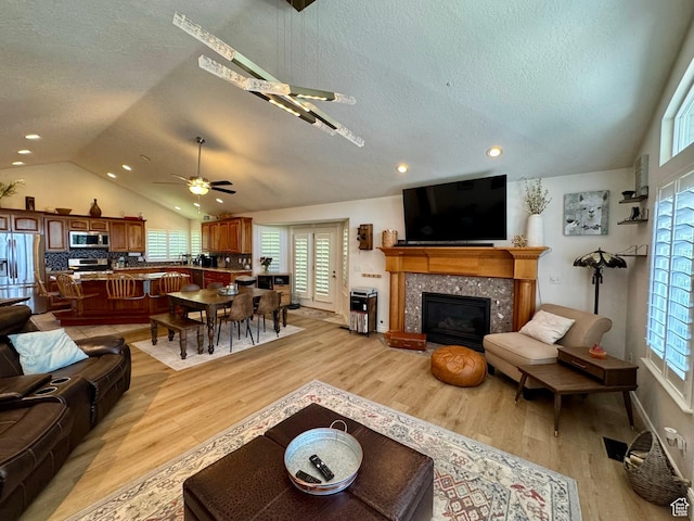 1710 N 2625 E, Layton, UT 84040 - living area featuring vaulted ceiling, a ceiling fan, a textured ceiling, light wood finished floors, and a tiled fireplace