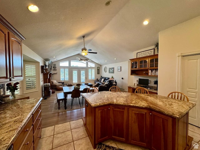 1710 N 2625 E, Layton, UT 84040 - kitchen featuring vaulted ceiling, ceiling fan, a center island, open floor plan, and light stone counters
