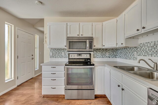 4733 S 3900 W, Roy, UT 84067 - kitchen with stainless steel appliances, a sink, white cabinets, light wood finished floors, and tasteful backsplash