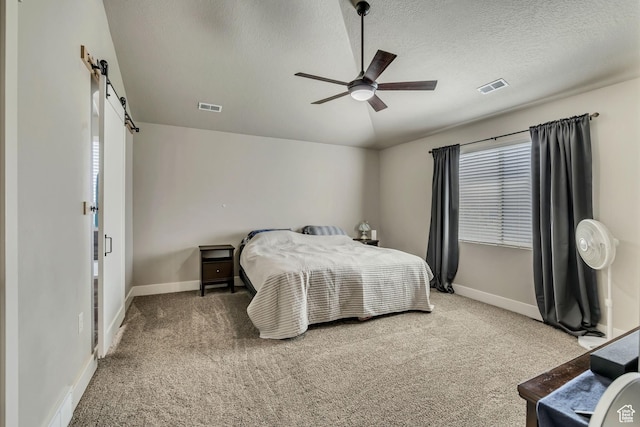 12884 S Tortoise Ln, Riverton, UT 84096 - carpeted bedroom with a barn door, baseboards, a textured ceiling, and a ceiling fan