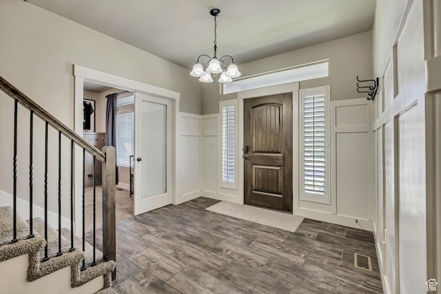 12884 S Tortoise Ln, Riverton, UT 84096 - foyer entrance with stairs, a chandelier, dark wood-style flooring, and a decorative wall