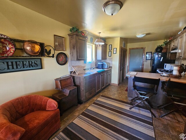 45465 W Airport Rd, Fruitland, UT 84027 - kitchen featuring under cabinet range hood, freestanding refrigerator, a chandelier, hanging light fixtures, and a desk