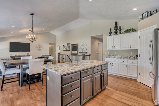 11743 S Silver Spur Ln, Draper, UT 84020 - kitchen with freestanding refrigerator, vaulted ceiling, white cabinetry, open floor plan, and a kitchen island