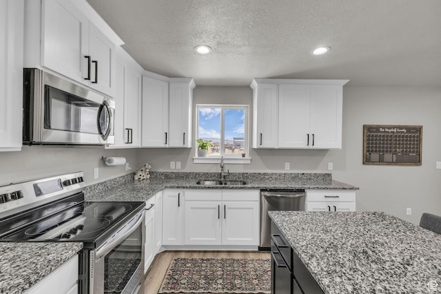 18616 Jefferson Ave, Eagle Mountain, UT 84013 - kitchen with stainless steel appliances, a sink, a textured ceiling, white cabinets, and light wood-style flooring