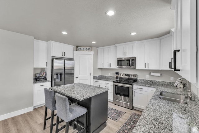 18616 Jefferson Ave, Eagle Mountain, UT 84013 - kitchen featuring stainless steel appliances, a sink, light wood-type flooring, light stone countertops, and recessed lighting