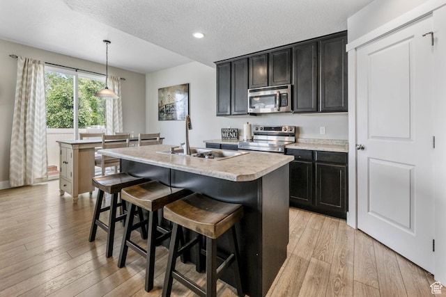 5564 W Baldrine Ct, Herriman, UT 84096 - kitchen with appliances with stainless steel finishes, a sink, light wood finished floors, light countertops, and a textured ceiling
