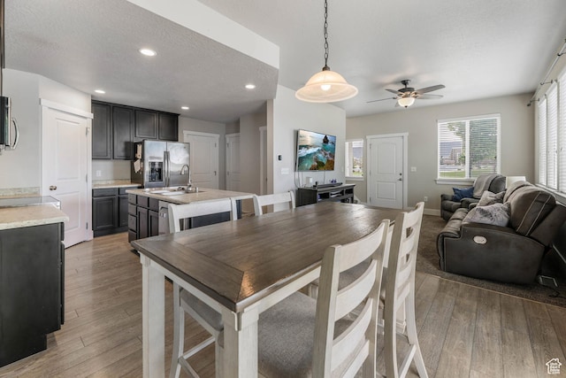 5564 W Baldrine Ct, Herriman, UT 84096 - kitchen featuring appliances with stainless steel finishes, a ceiling fan, light countertops, a kitchen island with sink, and light wood finished floors