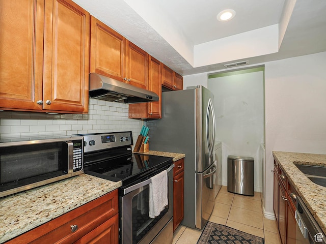 7208 S Station Creek Ln Unit 4B, Cottonwood Heights, UT 84047 - kitchen with stainless steel appliances, under cabinet range hood, light tile patterned flooring, backsplash, and light stone counters