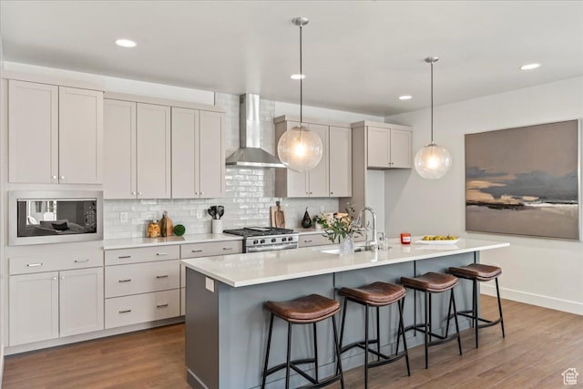7119 S Rocky Trl Unit 102, West Jordan, UT 84084 - kitchen with wall chimney range hood, a sink, built in microwave, stainless steel gas stove, and wood finished floors