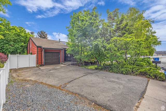 1054 E Lamplighter Dr, River Heights, UT 84321 - view of front of home featuring driveway, a gate, roof with shingles, and a garage