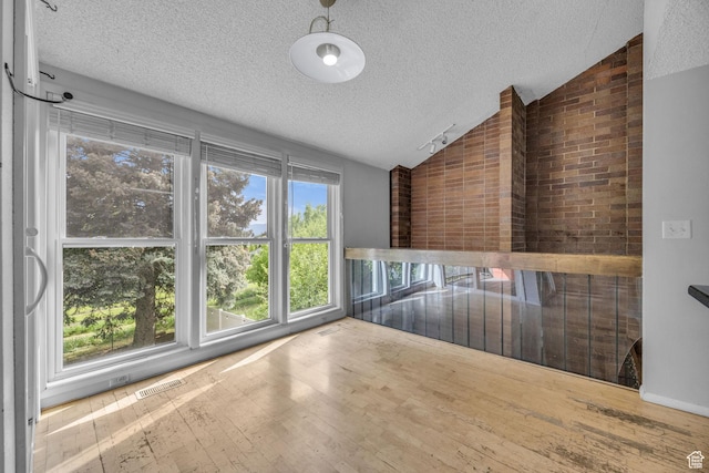 1054 E Lamplighter Dr, River Heights, UT 84321 - unfurnished room featuring vaulted ceiling, a textured ceiling, and wood finished floors