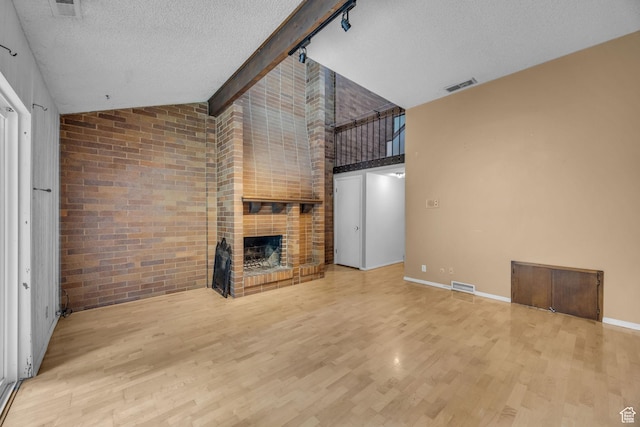 1054 E Lamplighter Dr, River Heights, UT 84321 - unfurnished living room featuring wood finished floors, a brick fireplace, a textured ceiling, high vaulted ceiling, and baseboards