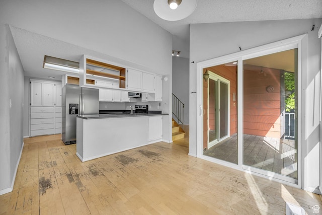 1054 E Lamplighter Dr, River Heights, UT 84321 - kitchen with stainless steel fridge, dark countertops, white cabinetry, light wood-style flooring, and vaulted ceiling