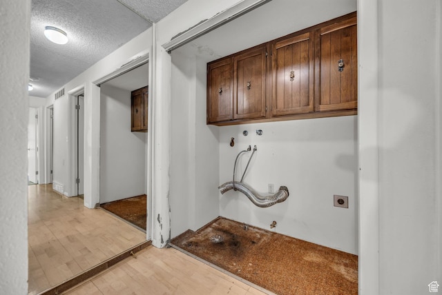 1054 E Lamplighter Dr, River Heights, UT 84321 - laundry room with cabinet space, light wood-style floors, gas dryer hookup, a textured ceiling, and hookup for an electric dryer