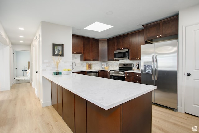 3644 S 860 E Unit 57, Salt Lake City, UT 84106 - kitchen featuring appliances with stainless steel finishes, a skylight, light wood finished floors, a peninsula, and dark brown cabinets