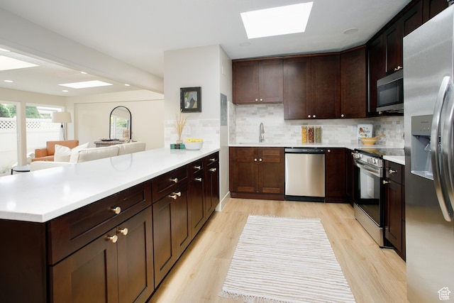 3644 S 860 E Unit 57, Salt Lake City, UT 84106 - kitchen with appliances with stainless steel finishes, a peninsula, a sink, a skylight, and light countertops