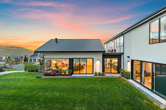 1620 W Brevia Ct Unit 25, Lehi, UT 84043 - back of property at dusk featuring a balcony, stucco siding, a yard, metal roof, and a standing seam roof