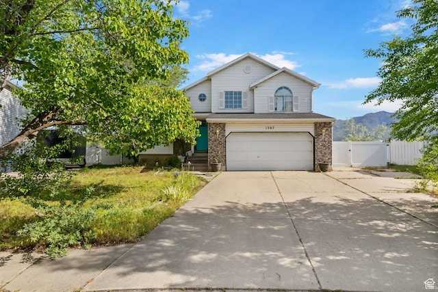 1367 E 3125 N, Layton, UT 84040 - traditional-style house with a gate, an attached garage, concrete driveway, a mountain view, and brick siding