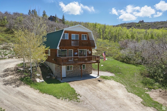 10246 E Lake Pines Dr Unit 1020, Heber City, UT 84032 - view of front facade with a gambrel roof, stone siding, a view of trees, driveway, and a balcony
