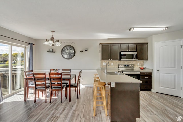 3864 E Cascade Rd, Eagle Mountain, UT 84005 - kitchen featuring stainless steel appliances, a sink, a chandelier, light wood finished floors, and dark brown cabinetry