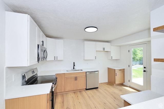 4673 W 5255 S, Kearns, UT 84118 - kitchen with appliances with stainless steel finishes, a sink, light wood-style floors, white cabinets, and a textured ceiling