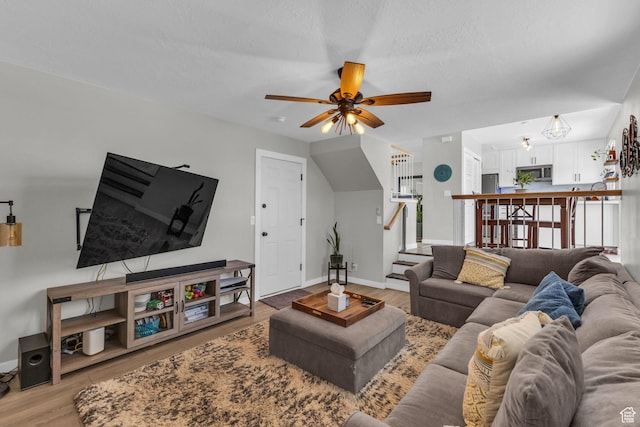 6169 Longmore Dr, Salt Lake City, UT 84118 - living room featuring light wood-style flooring, ceiling fan, stairs, and baseboards