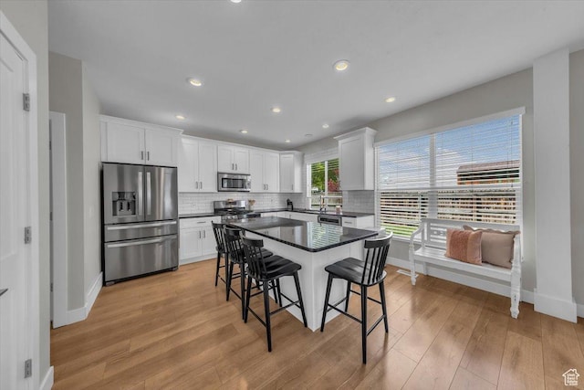 441 E Crape Myrtle Cir, Draper, UT 84020 - kitchen with stainless steel appliances, dark countertops, a breakfast bar, baseboards, and light wood finished floors