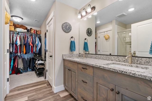 641 E Green Springs Way Unit 324, South Weber, UT 84405 - full bathroom with a stall shower, double vanity, a spacious closet, wood finished floors, and a textured ceiling