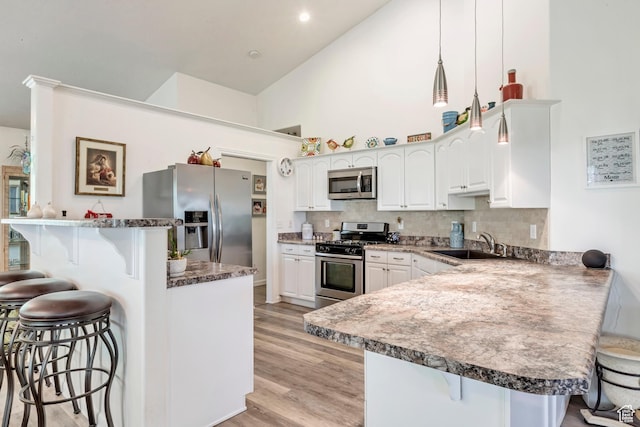 3286 N Piute Dr, Provo, UT 84604 - kitchen with appliances with stainless steel finishes, a kitchen breakfast bar, a peninsula, a sink, and high vaulted ceiling