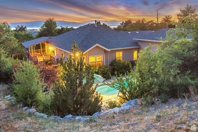 3286 N Piute Dr, Provo, UT 84604 - back of house at dusk with roof with shingles, an outdoor pool, and a wooden deck