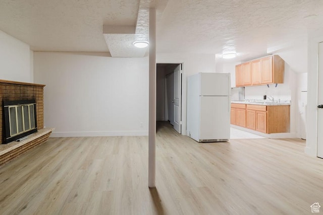 171 E 200 N, Orem, UT 84057 - unfurnished living room with a textured ceiling, light wood-type flooring, a sink, baseboards, and a brick fireplace